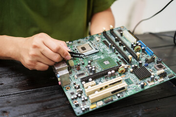 Technician carefully repairs a computer circuit board, using precision tools to address hardware...