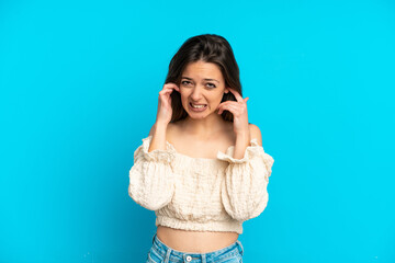 Young caucasian woman isolated on blue background frustrated and covering ears