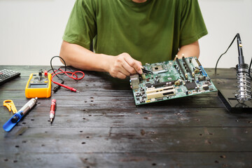 Technician carefully repairs a computer circuit board, using precision tools to address hardware...