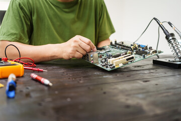 Technician carefully repairs a computer circuit board, using precision tools to address hardware...