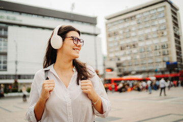 Young caucasian woman listening to music or audio book in the city	