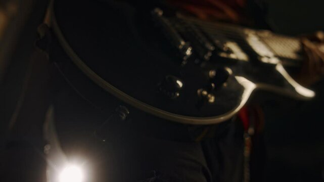 Close-up of hands of unrecognizable male musician pluging in black electric guitar before live performance on stage or concert hall