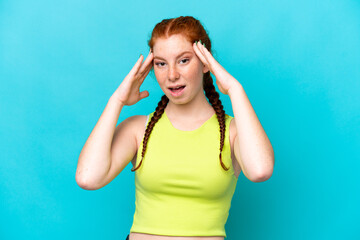 Young reddish woman isolated on blue background with surprise expression