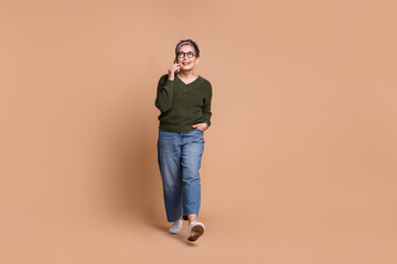 Naklejka premium Photo of charming pretty mature woman wear green stylish clothes look up empty space isolated on beige color background