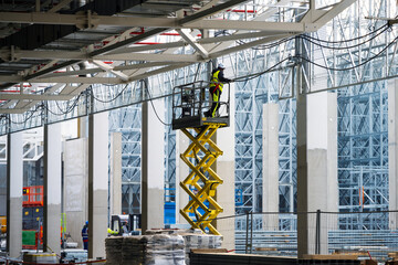 Electricians installing cables on cable trays working at height on construction site