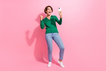 Full length photo of young woman celebrate achievement in mobile game girl raised fist phone using...