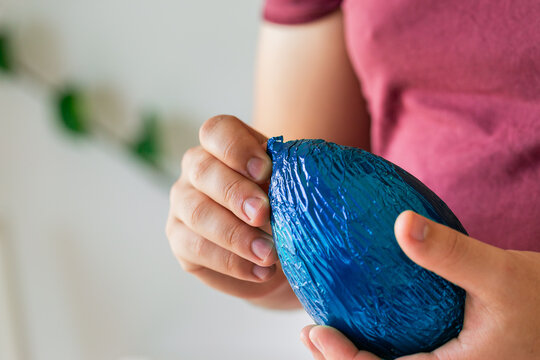 Person unwrapping foil from large easter egg