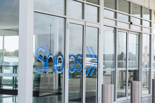 Entrance to shopping mall with sign to shops and glass windows and automatic doors