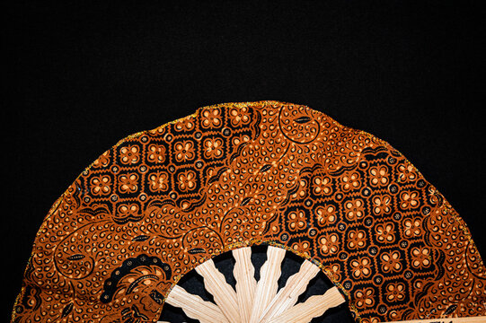 traditional hand fan, a hand fan made of wood and patterned fabric. 