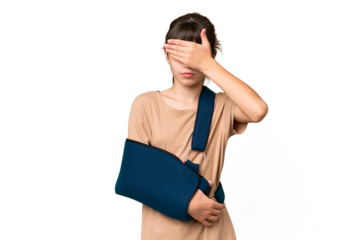Little caucasian girl with broken arm and wearing a sling over isolated background covering eyes by hands. Do not want to see something
