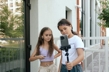 Multiethnic elementary middle school. Girls make videos for tiktok and uses the phone and headphone in the school yard. Gen Alpha. Part of a series. Concept education and UGC