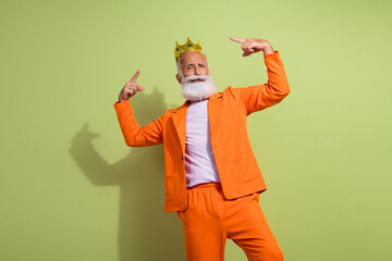 Photo of funny extravagant man point fingers golden crown wear orange suit isolated on green color...
