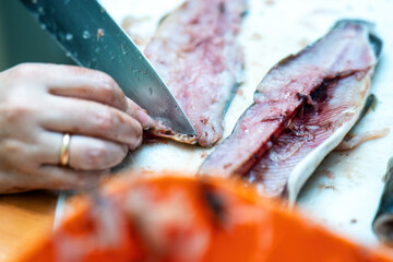 close-up of feminine hands skillfully slicing vibrant red fish with a large knife, embodying the art of culinary preparation and the joy of creating delicious meals