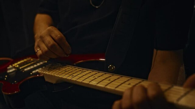 Close-up of hands of unrecognizable male musician plugging in electric guitar, sound checking and getting ready for live performance im concert hall