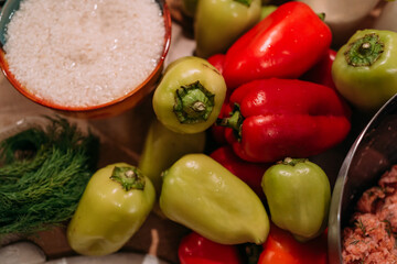 colorful assortment of fresh bell peppers in the kitchen, vibrant green and red peppers with other ingredients on the table, preparing for cooking. ingredients for stuffed peppers