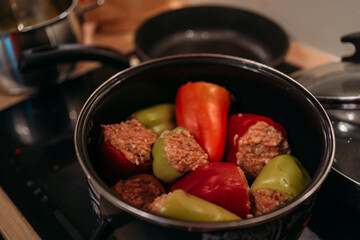 cooking homemade stuffed peppers with minced meat, kitchen scene with pot on stove, preparing...