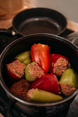cooking homemade stuffed peppers with minced meat, kitchen scene with pot on stove, preparing...