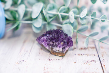 Natural stone amethyst lilac, light background of silver eucalyptus branch.