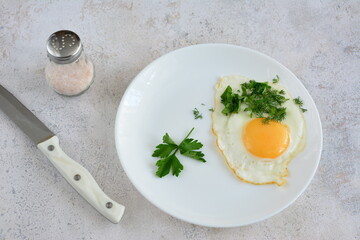 a plate of fried eggs, parsley and a kitchen knife on a table flat lay 