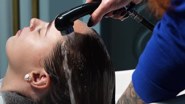 a beautiful young girl with short hair and a bob haircut is doing a procedure in a beauty salon. Hair master doing coloring and tone to client's hair close-up