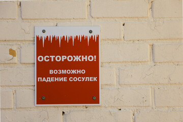 A Russian Red Caution Sign On A Brick Wall Warns Of Potential Falling Icicles, Emphasizing Safety...