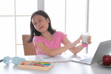 Asian Elementary school girl doesn't like to drink milk, makes gestures refusing to drink milk...