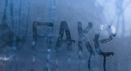 FAKE word written on wet glass.