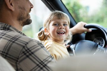 Man with his daughter holding steering wheel inside car, closeup