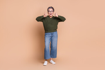Fototapeta premium Photo of cheerful glad lovely senior lady wear green stylish clothes demonstrate thumb up isolated on beige color background