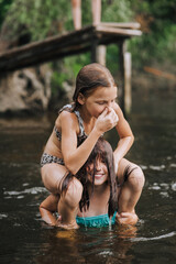 Fototapeta premium Two girlfriends girls, cheerful smiling children play, laugh, jump in the water in the lake on the sea. Photography, portrait, friendship concept, rest.