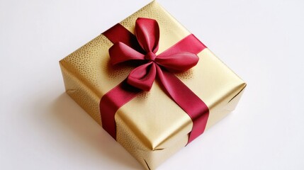 Obraz premium Gold-wrapped New Year present with a large red ribbon, isolated on white, emphasizing luxury and festive spirit.