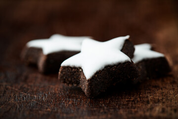 Christmas cookies (cinnamon stars) and brown sugar on dark background. Close up.