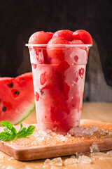 Refreshing Watermelon Balls with Crushed Ice served in plastic cup isolated on dark background side view of healthy vitamin salad