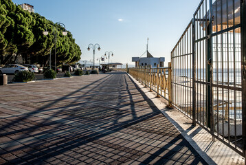 A long embankment along the sea with a fence.