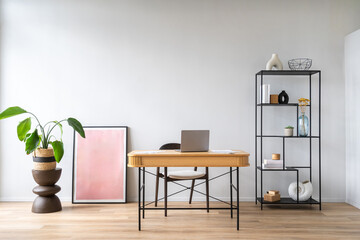 Modern workspace with a stylish wooden desk, art work, potted plant and open shelving
