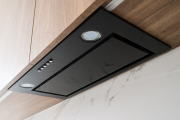 Modern kitchen range hood installed under wooden cabinets in a contemporary home