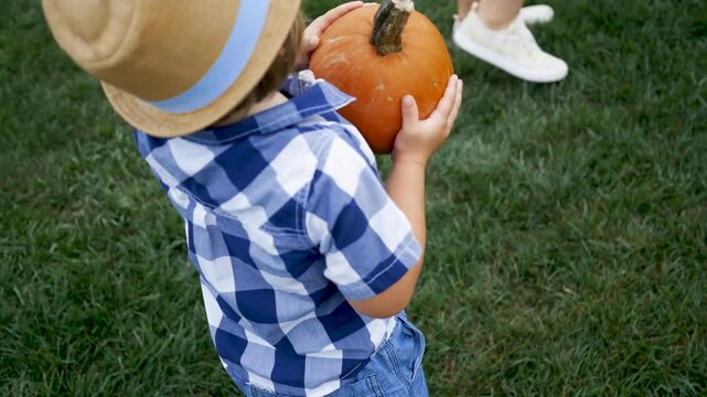 Toddler carrying pumpkin at fall festival