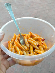 a hand of a man eating macaroni on break from work