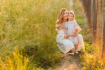 Young mother sitting with her daughter in the grass. Copy space