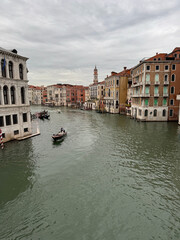 Obraz premium A view of canal in Venice with a gondola in the water and beautiful buildings lining the sides. The sky is overcast but the water is still sparkling. The scene is peaceful and serene.