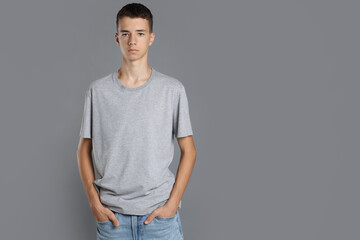 Obraz premium Teenage boy wearing t-shirt on grey background, space for text