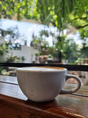 Vertical shot of a cup of hot latte art coffee on wooden table and blurred background.