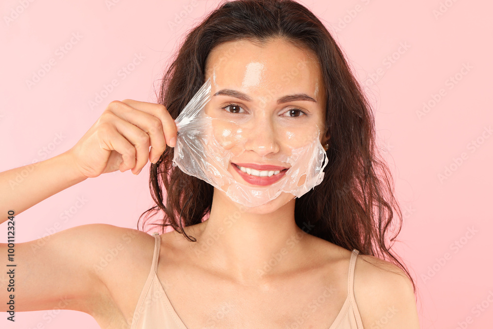 Sticker Smiling woman peeling off face mask on pink background