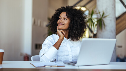 Thoughtful Businesswoman Working on Laptop in Modern Office