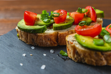 Avocado toast topped with tomato and green onion on a slice of carrot bread