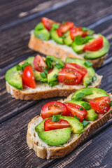 Avocado toast topped with tomato and green onion on a slice of carrot bread