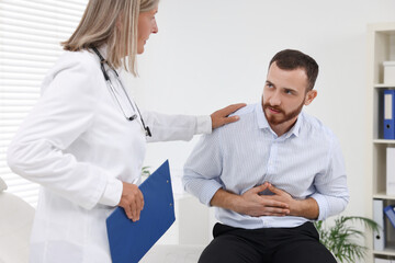 Doctor consulting patient with stomach pain in clinic