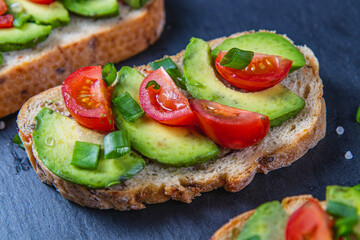 Avocado toast topped with tomato and green onion on a slice of carrot bread