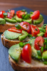 Avocado toast topped with tomato and green onion on a slice of carrot bread