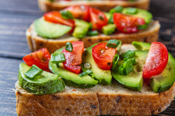 Avocado toast topped with tomato and green onion on a slice of carrot bread